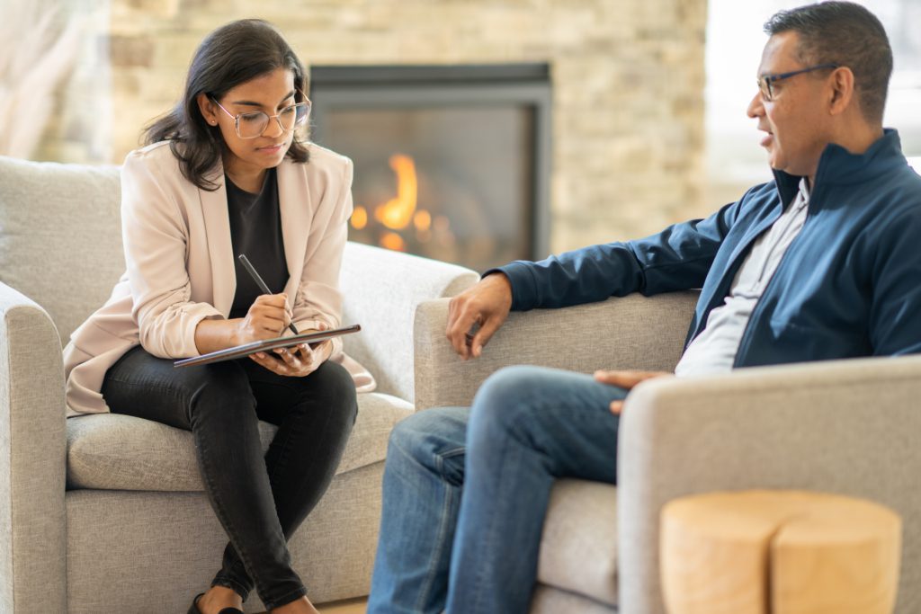 An older man explains his problems to his therapist, who takes notes attentively