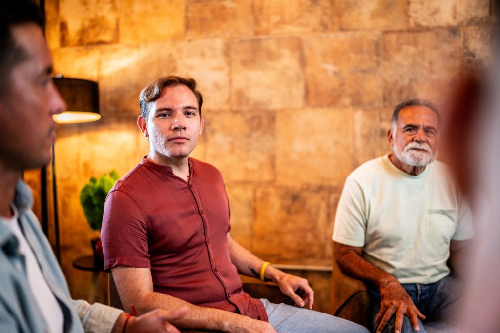 A man sits among peers during a group therapy session