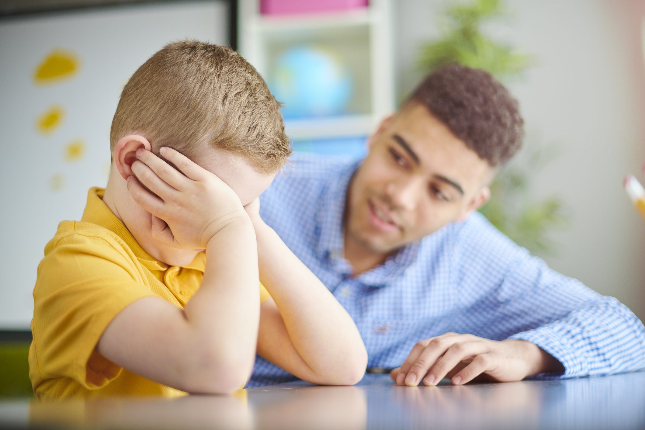 Upset school boy is comforted by teacher.