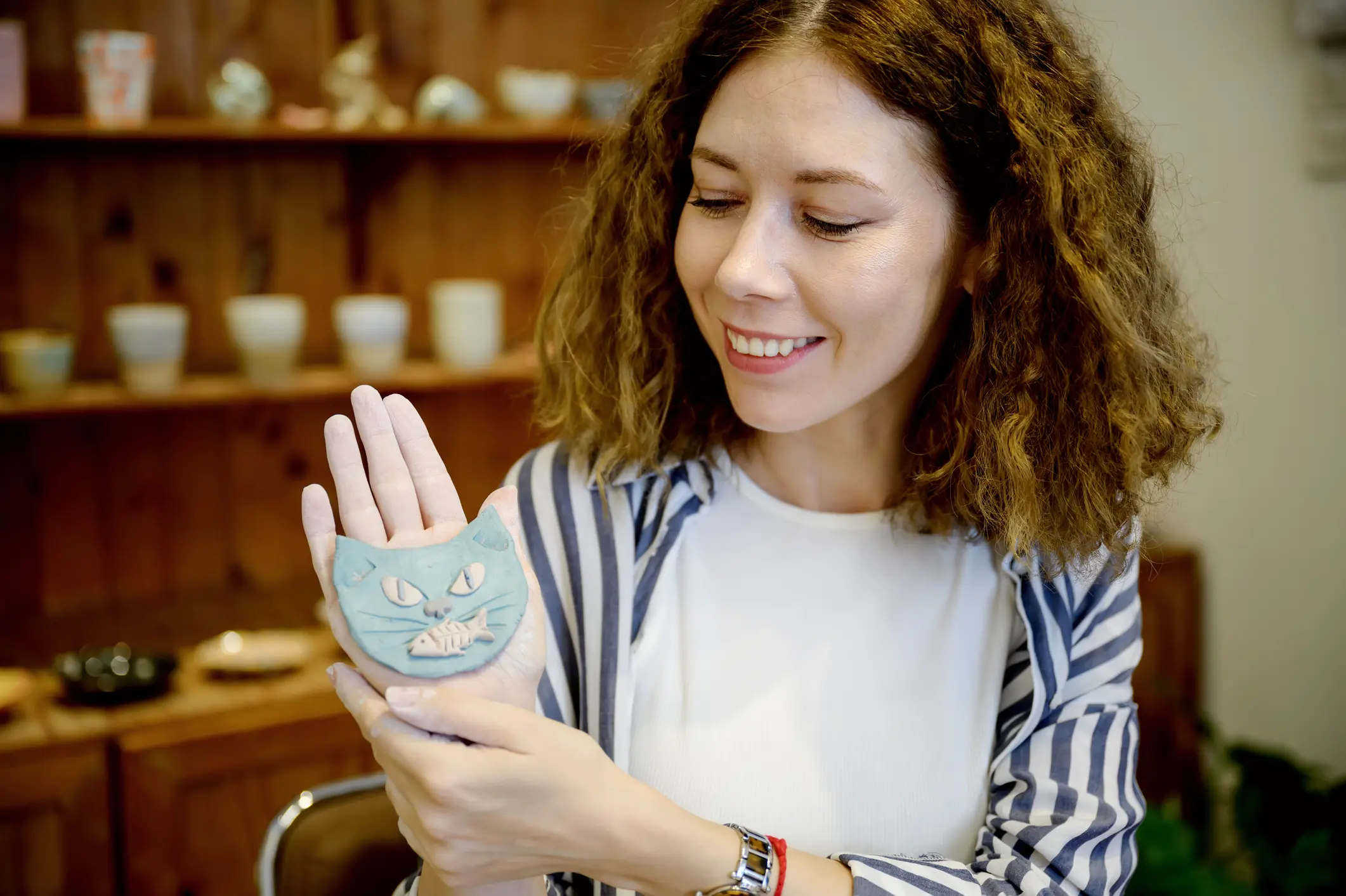 Proud woman holding cat sculpture artwork.